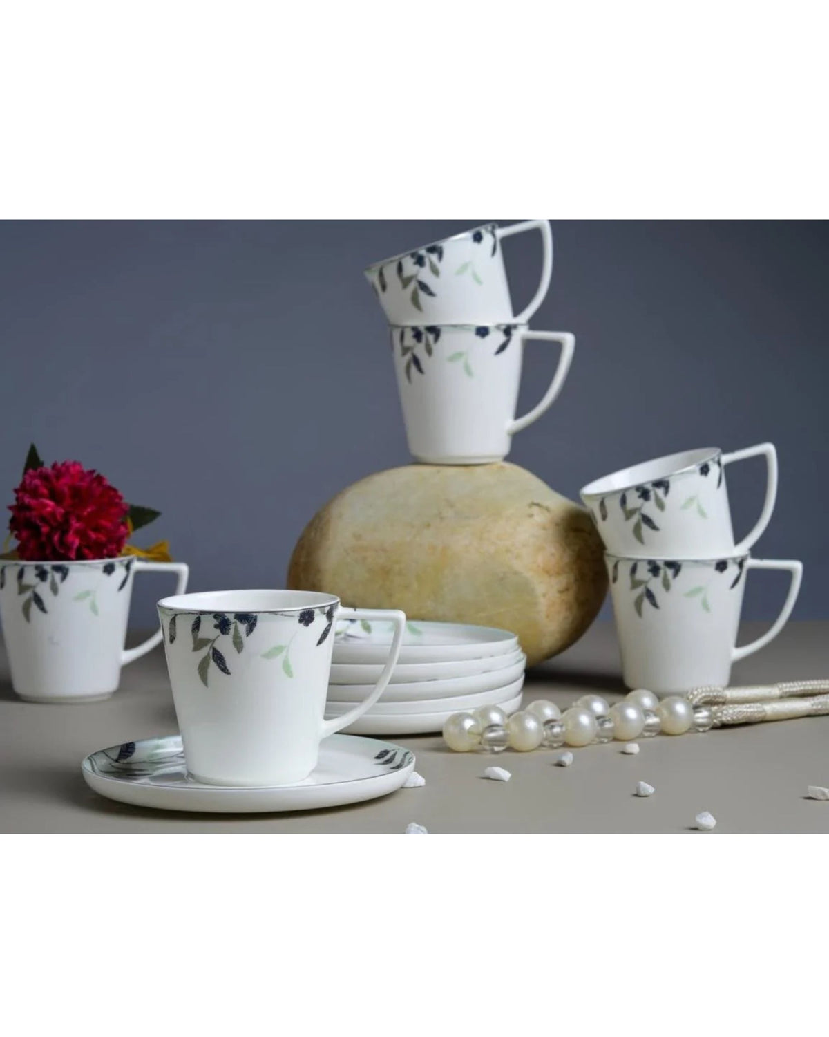 Six white floral print coffee mugs with matching saucers and plates.
