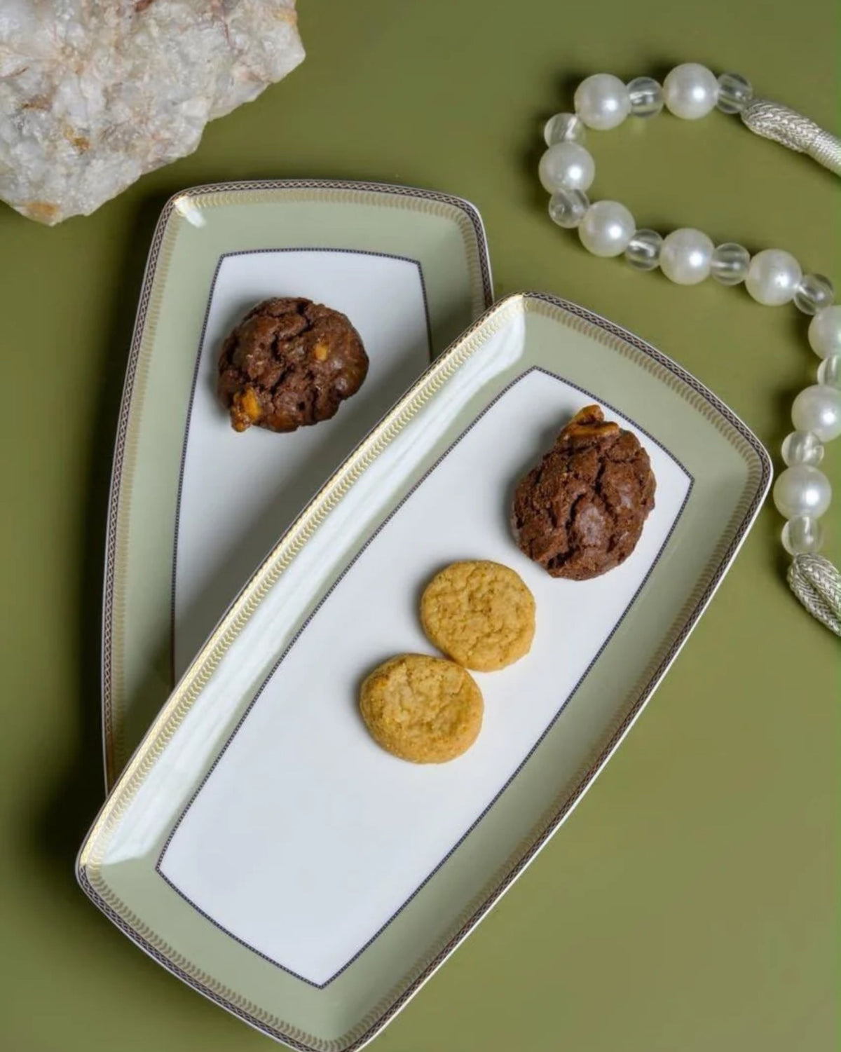 Two rectangular porcelain serving plates with sage green and gold borders