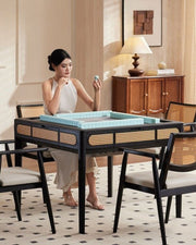 Mahjong game table with black top, wicker chairs, and tiled playing area