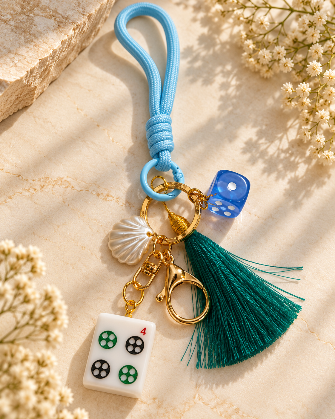 Blue mahjong tile keychain with gold rings and green tassel, blue braided loop