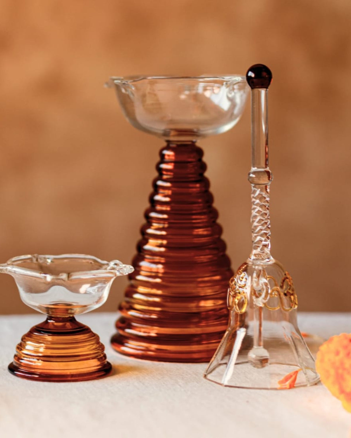 Crystal glass puja thali set with clear cups on amber and copper ribbed stands