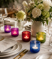Colored glass votive candle holders with lit tealights in blue, green, red, purple