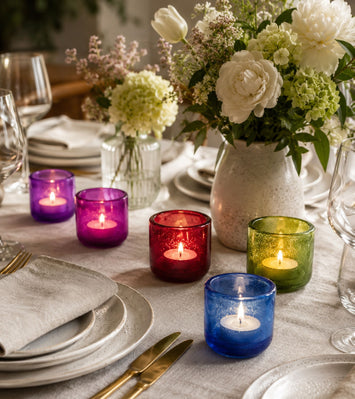 Colored glass votive candle holders with lit tealights in blue, green, red, purple