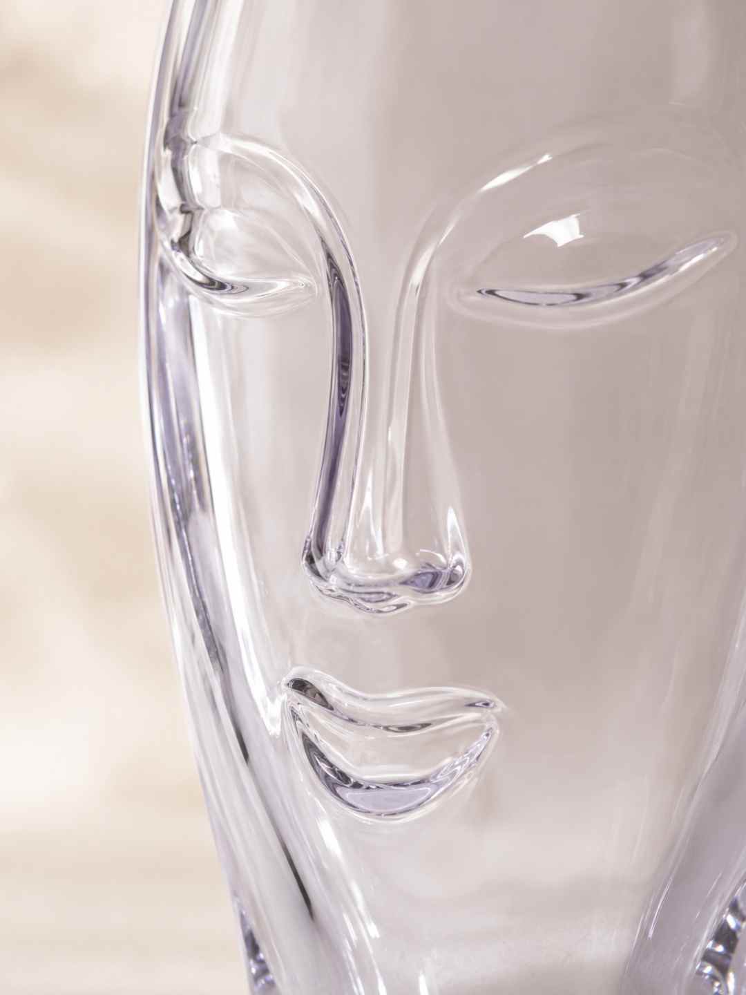 Clear glass face vase close-up, sculpted profile relief on the front