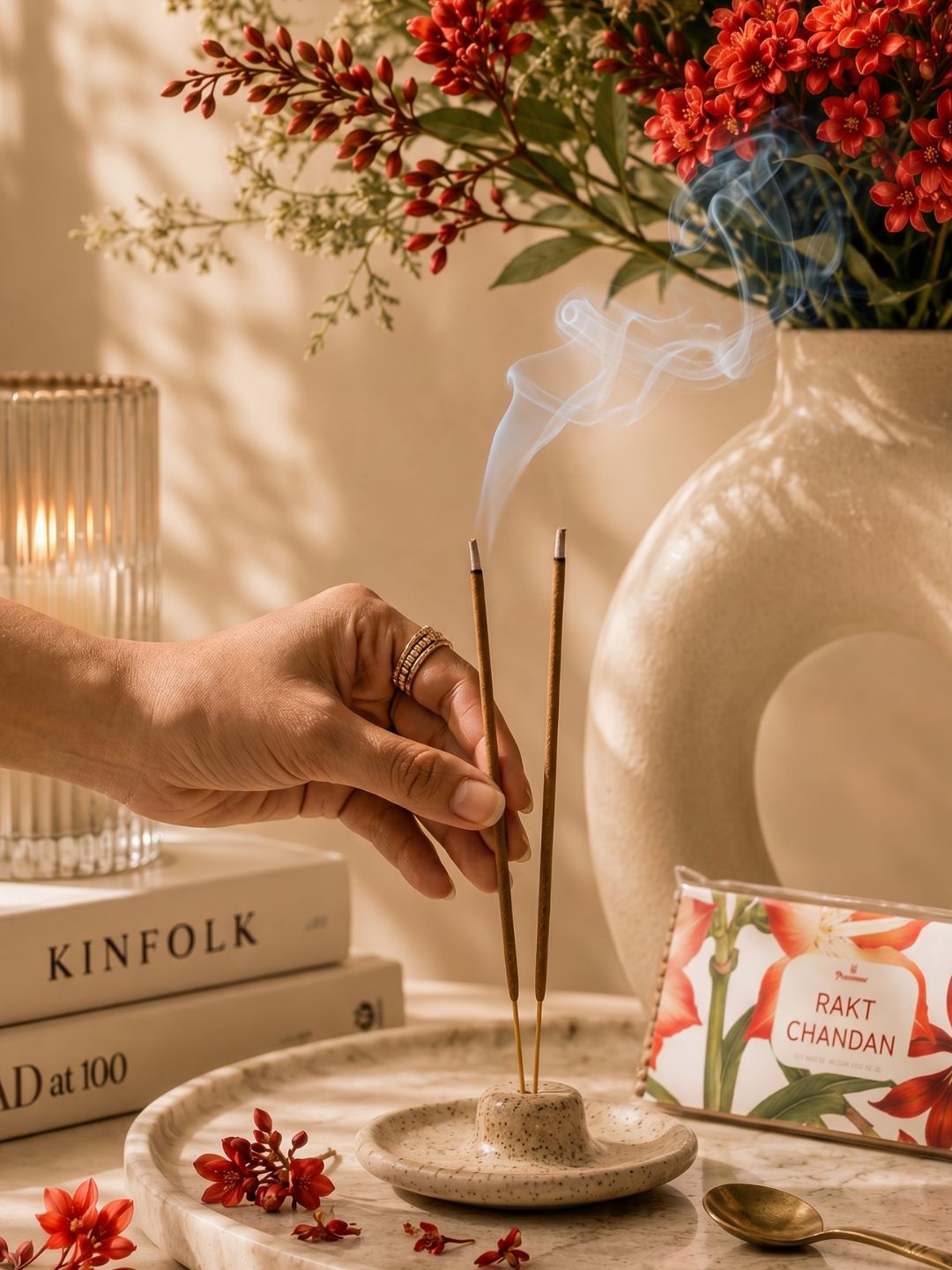 Incense sticks being lit with hand, smoke rising, and floral incense pack nearby