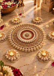 Round decorative rangoli with floral border and small oil lamps on beige surface