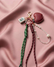Mahjong keychain with red leather apple charm, tassel cords, and pearl bead loop