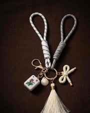White bow keychain with mahjong tile, shell charm, tassel, and small bow charm