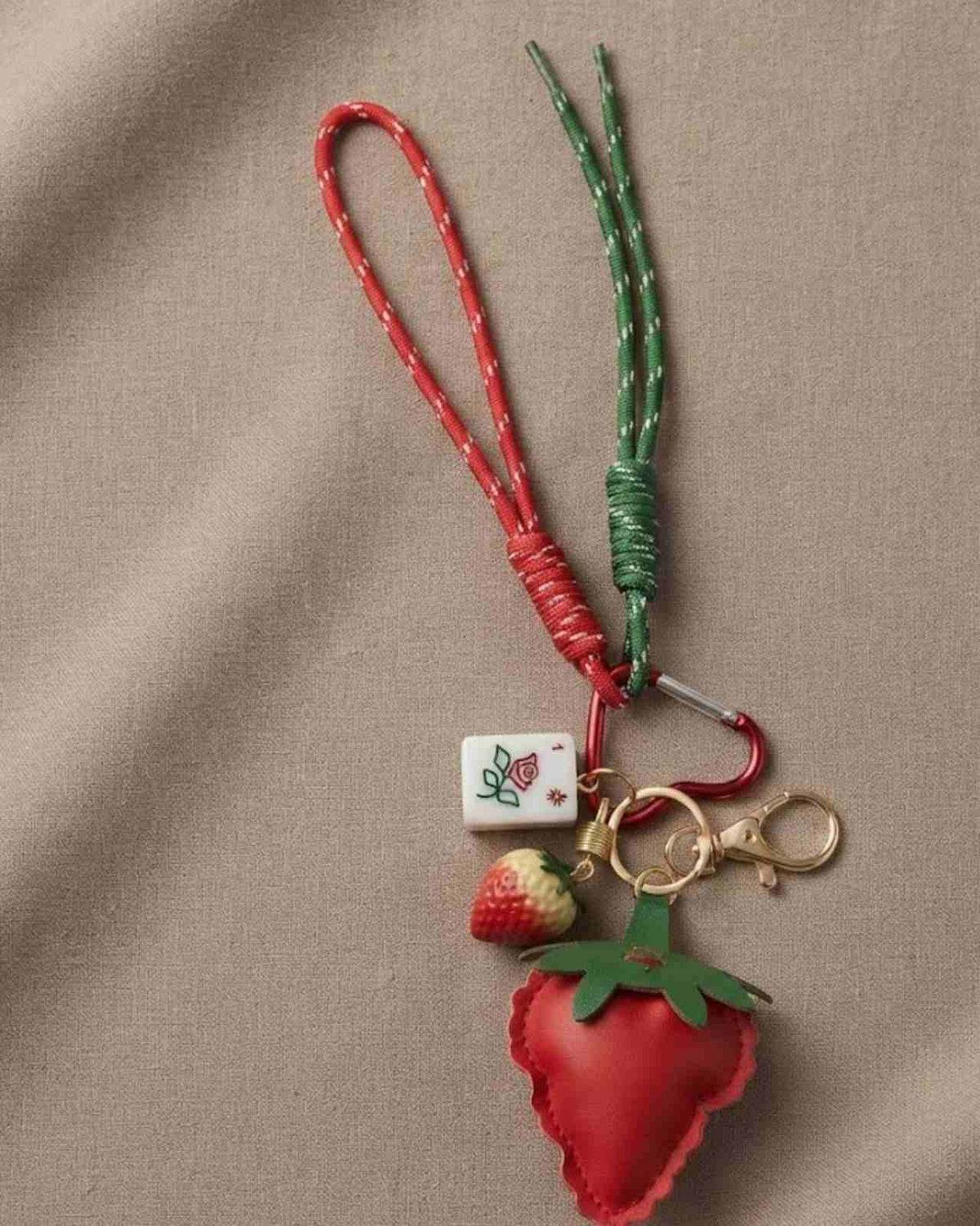 Strawberry mahjong keychain with red beaded cord, green leaves, and gold key rings