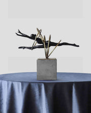 Black and gold balance sculpture with gold rods on gray square base