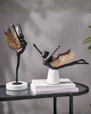Winged grace sculpture with black metal bird, gold wings, on round white base