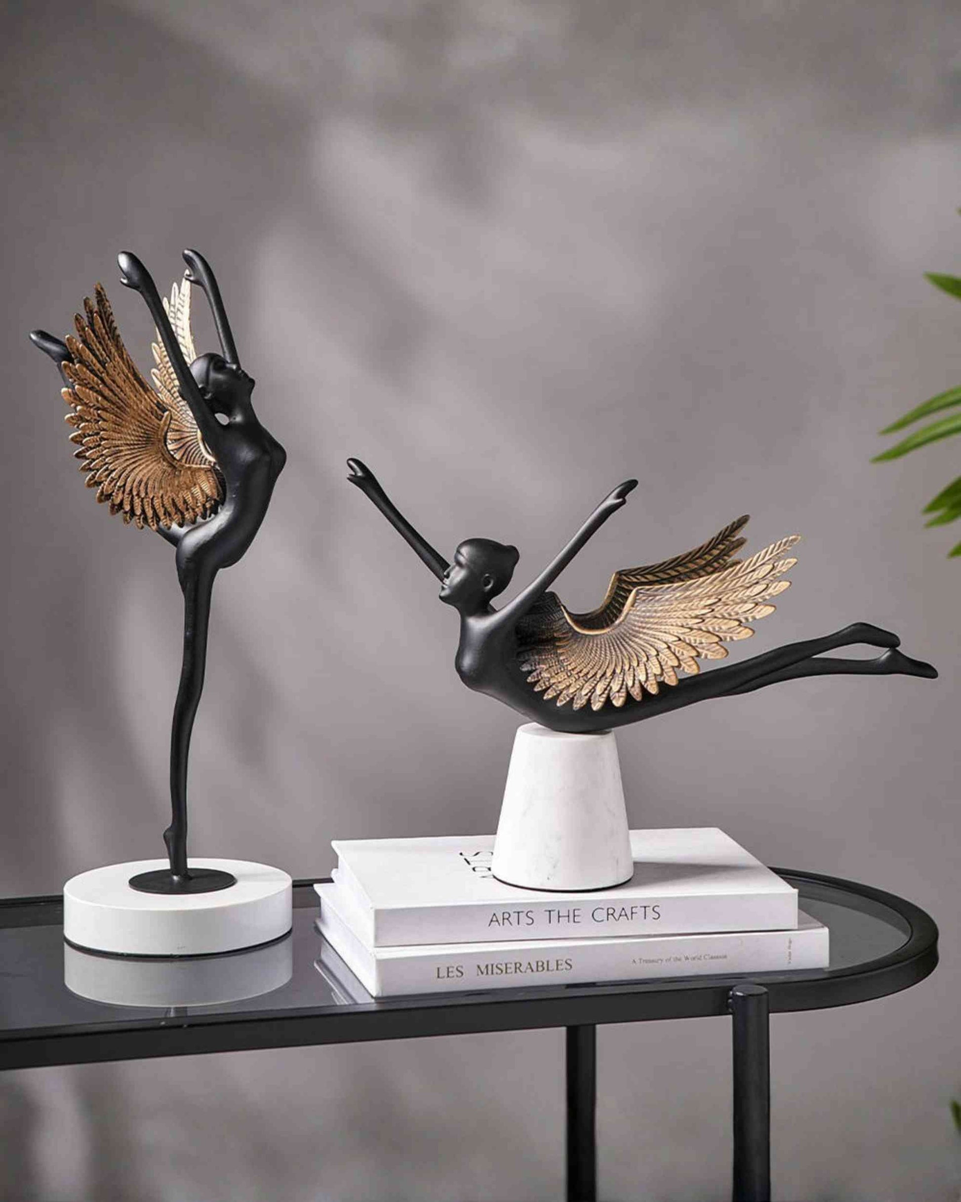 Winged grace sculpture with black metal bird, gold wings, on round white base