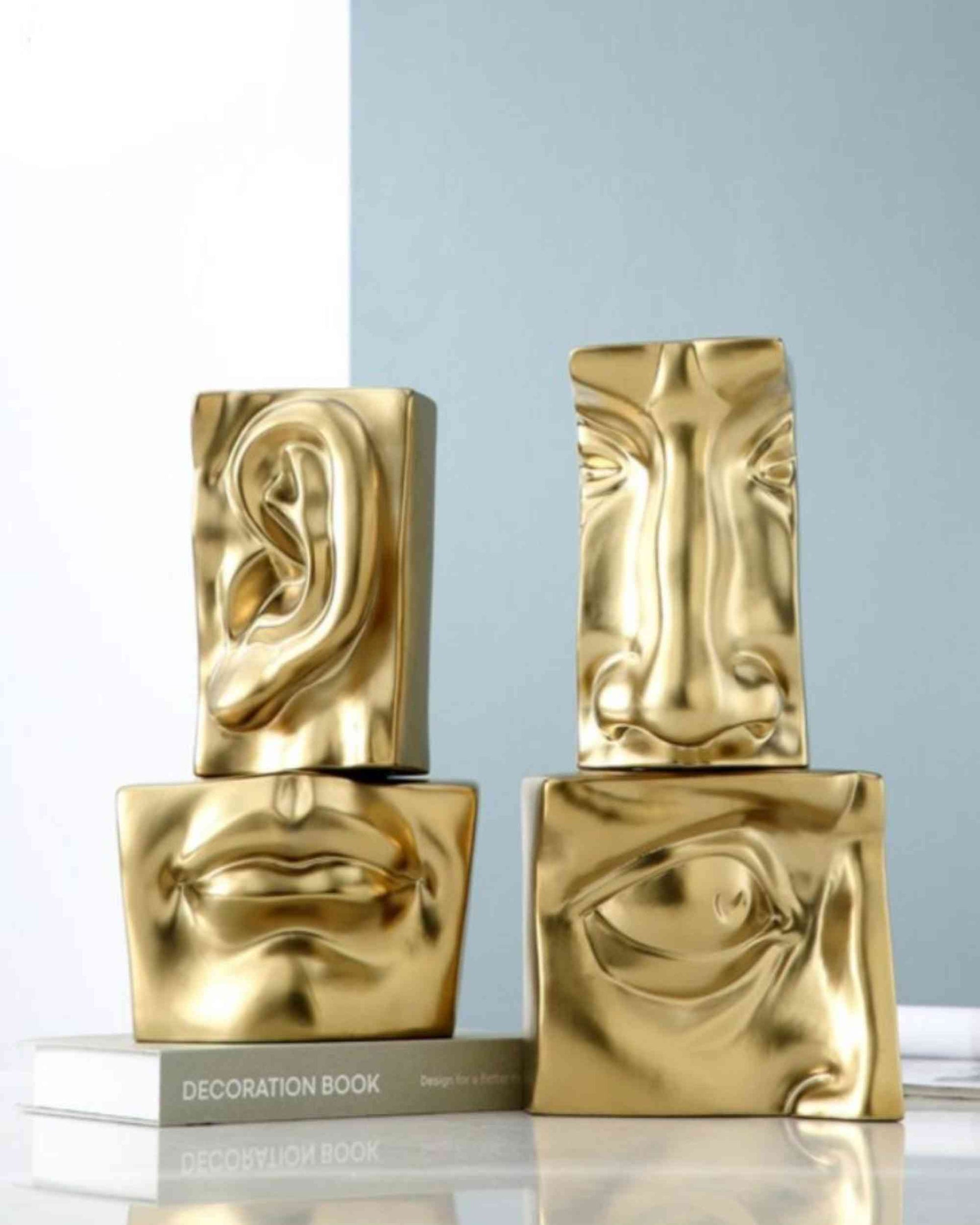 Gold resin sculptural blocks, two pieces stacked with embossed face profiles