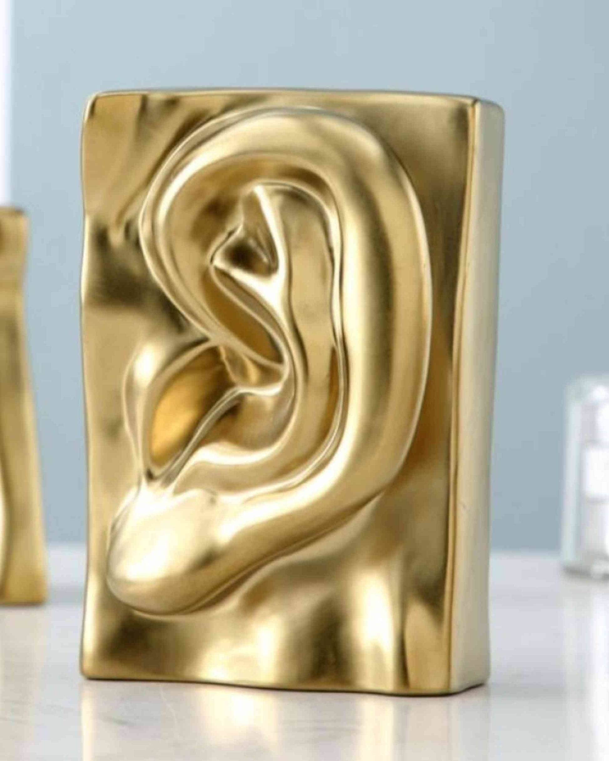 Gold resin sculptural block with embossed ear-like profile, rounded swirl