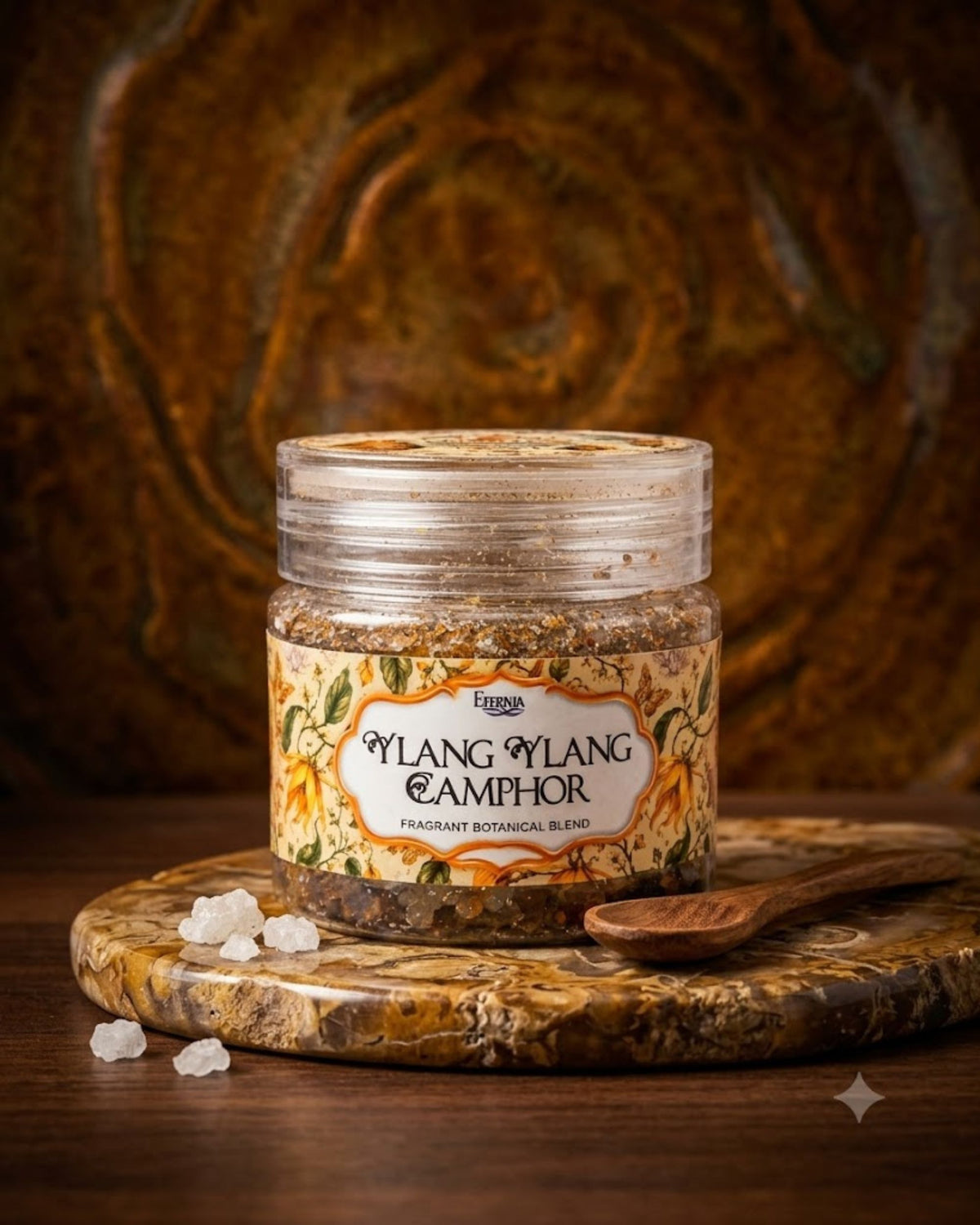 Glass fragrance jar with gold-toned lid and Ylang Ylang Camphor label, on wooden coaster