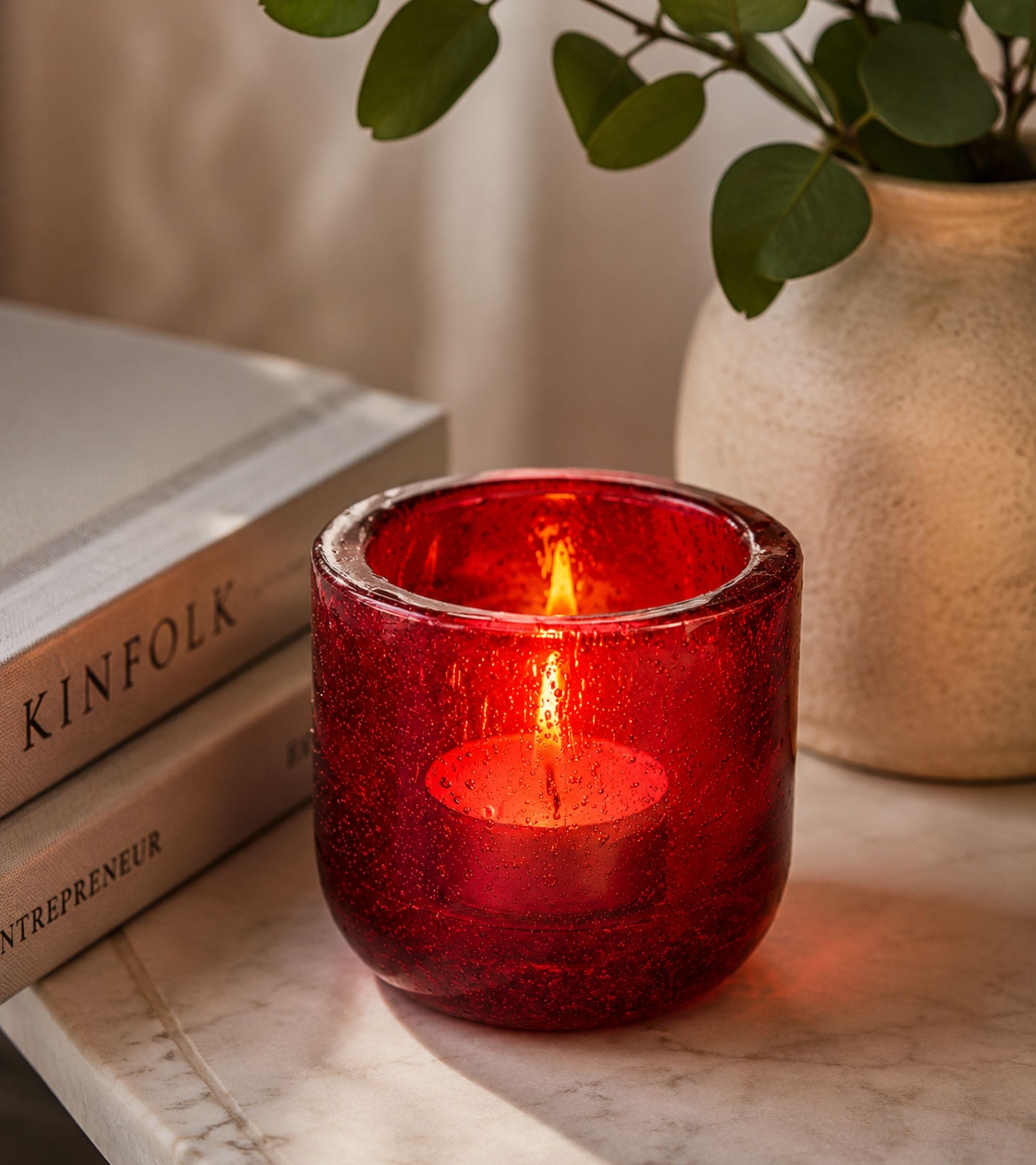 Red glass votive candle holder with lit tealight inside