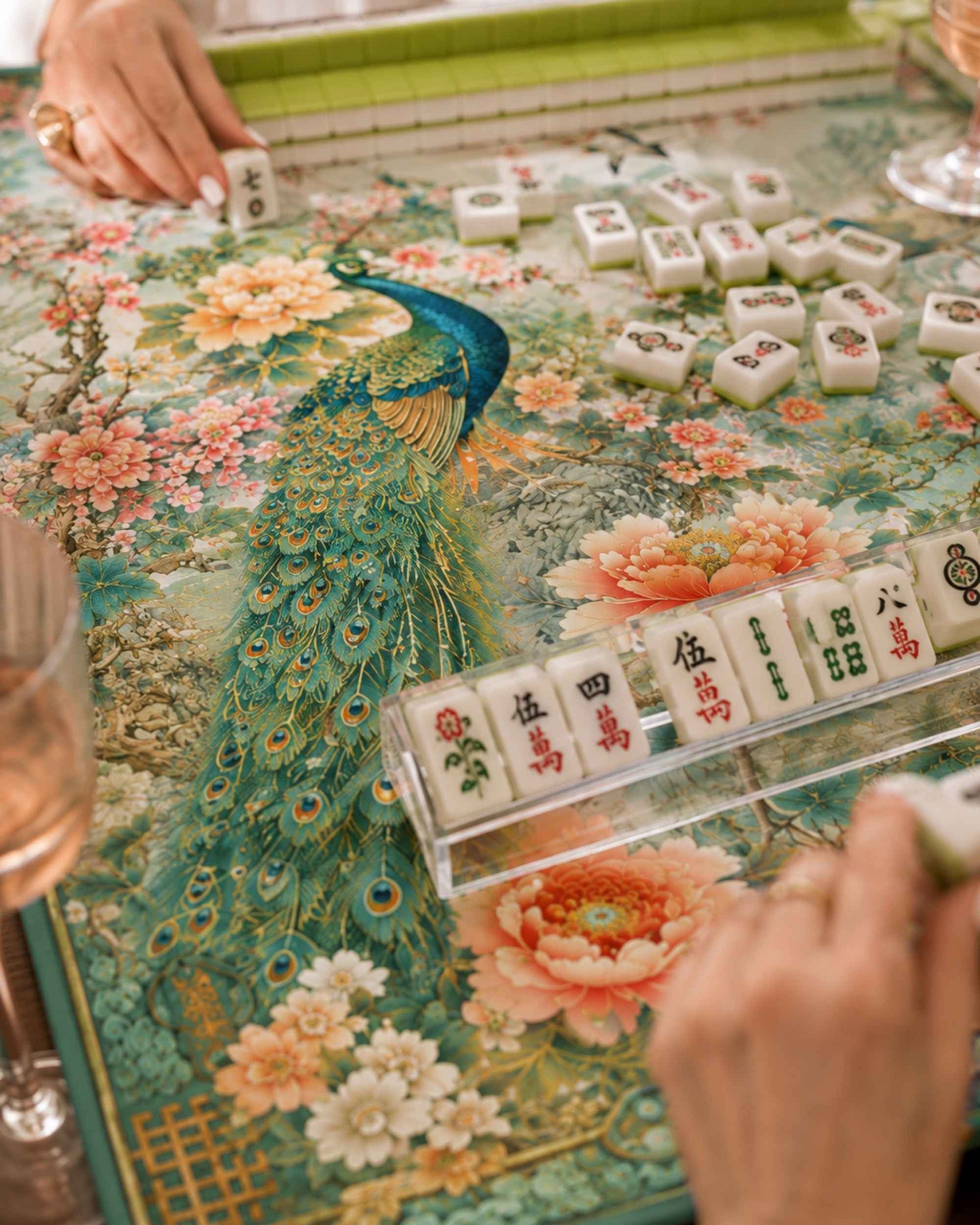 Teal floral mahjong table mat with peacock artwork and mahjong tiles in play