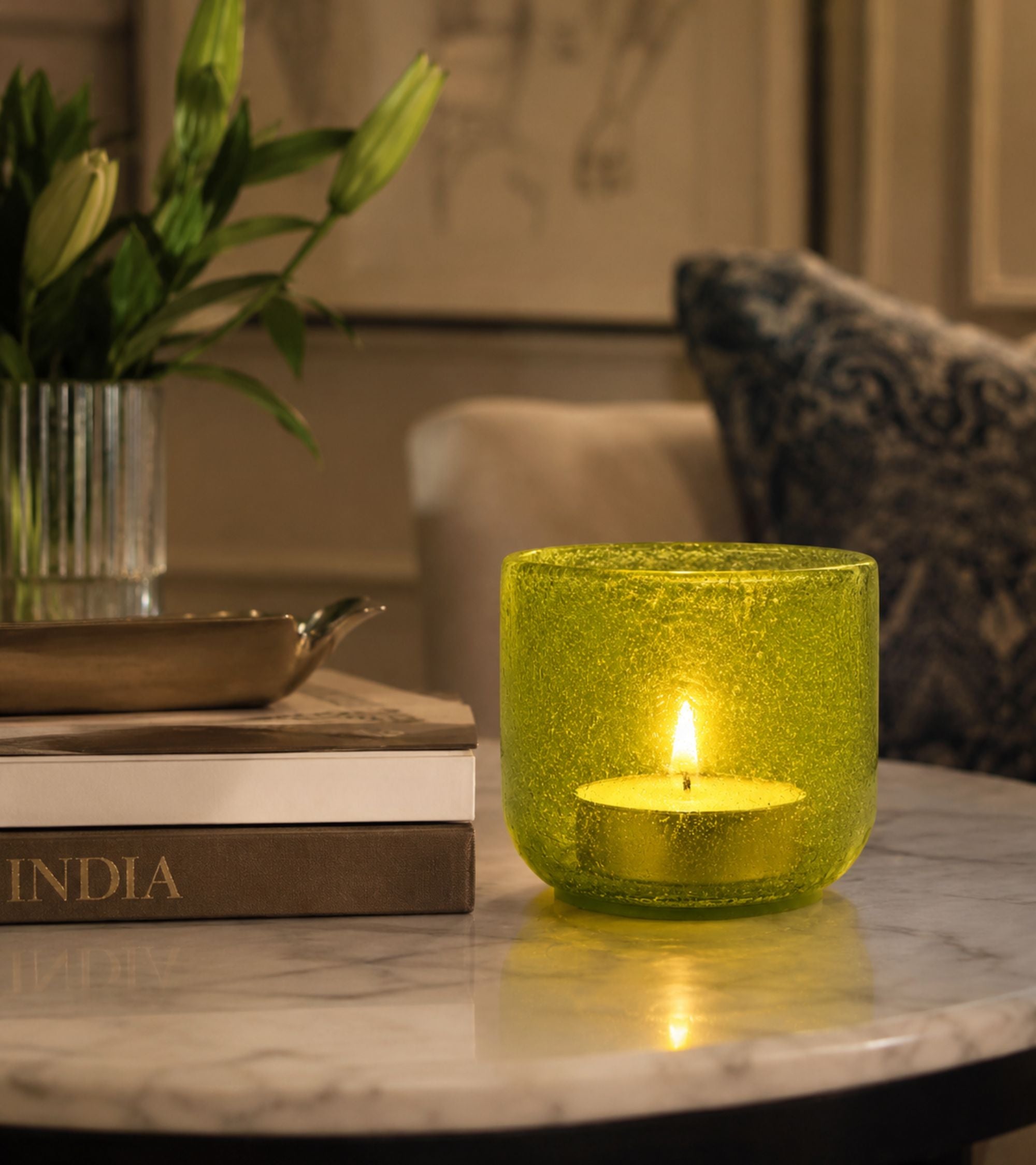Green glass votive candle holder with lit tealight candle inside