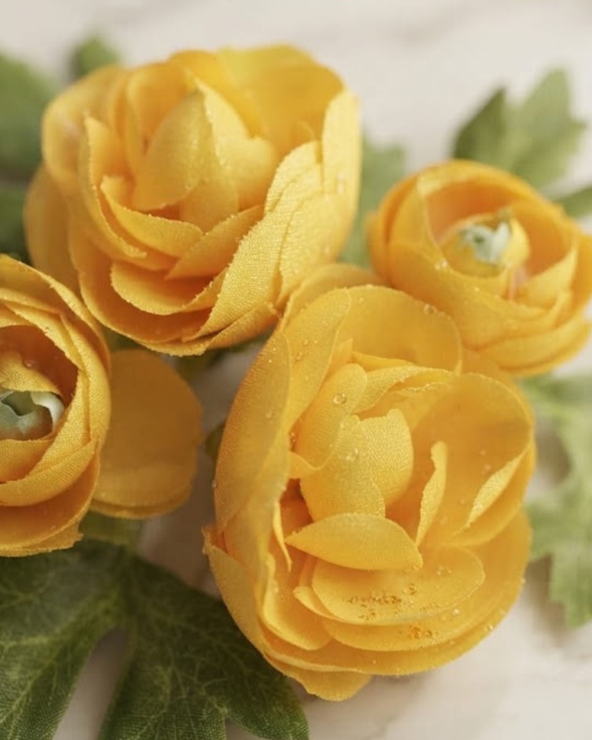 Artificial yellow rose flowers with green leaves in a cluster, close-up view