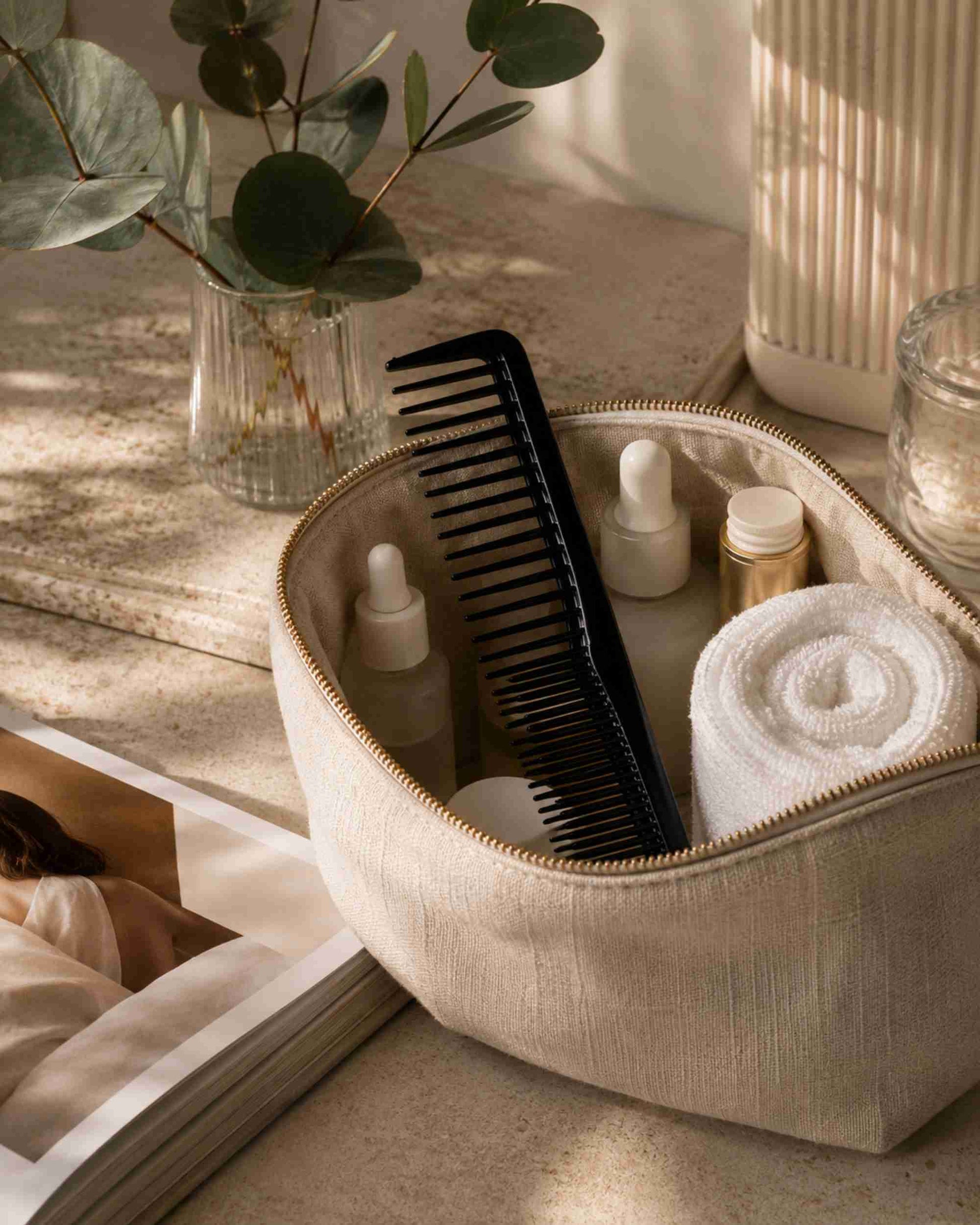 Black fine-tooth styling comb with wide teeth, shown in a zip pouch.