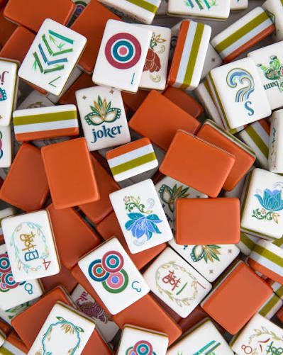 Mixed pile of orange and white melamine mahjong tiles with suit icons and joker tiles