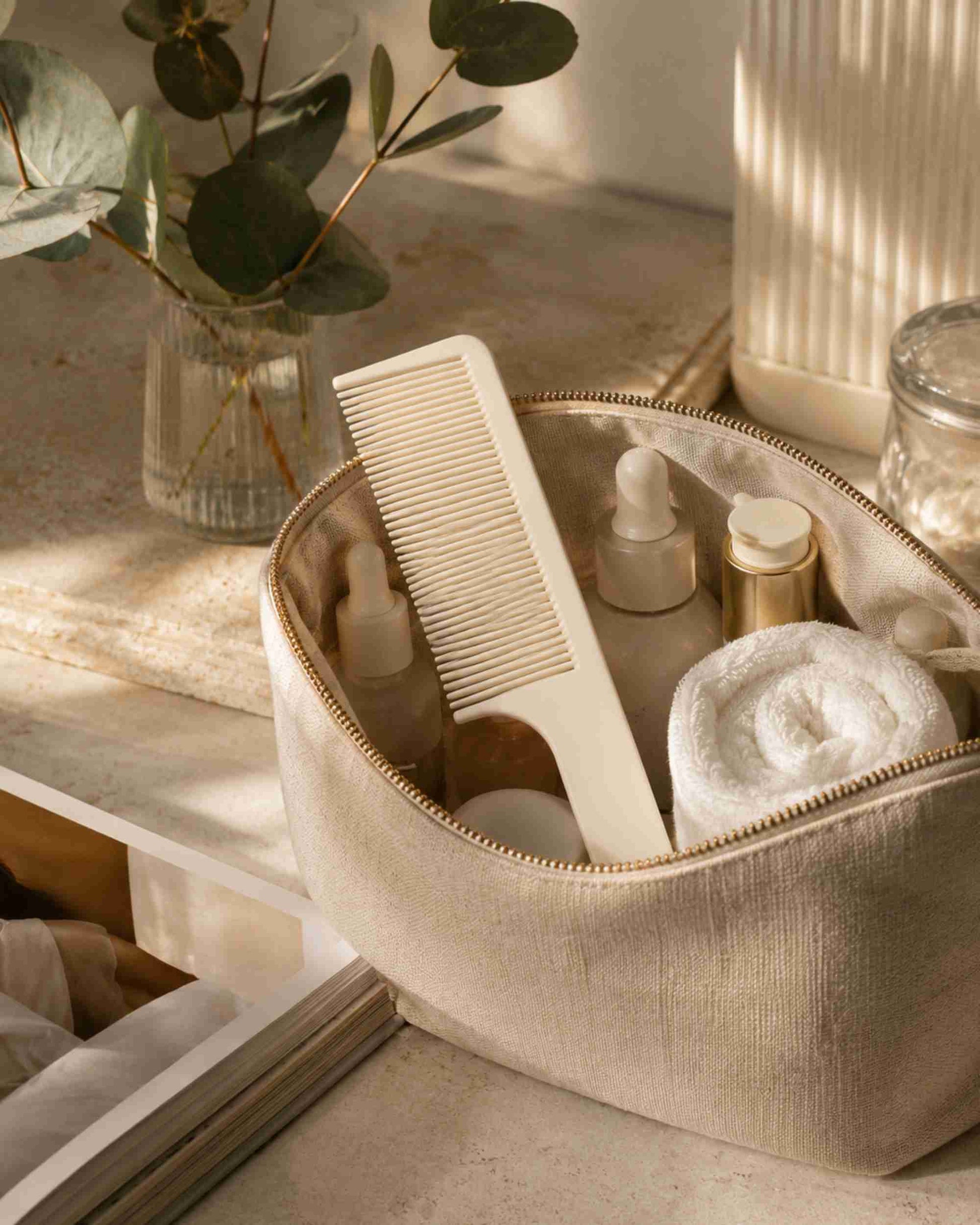 White fine-tooth comb stored in a zip pouch with other hair care items.